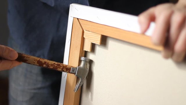 small jewelry repair hammer for hours, knocking on wood and coke is driven into the wooden subframe. The artist prepares a canvas for painting. The soft sunlight. in the morning sun flying dust. HD
