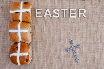 Easter - Hot cross buns with Easter in wooden letters on burlap background
