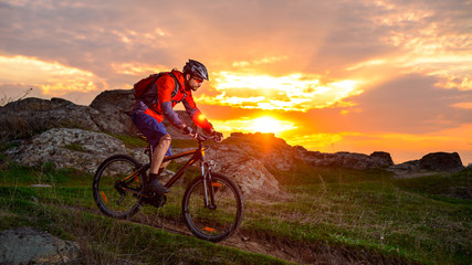 Cyclist Riding Mountain Bike on the Spring Rocky Trail at Beautiful Sunset. Extreme Sports and Adventure Concept.