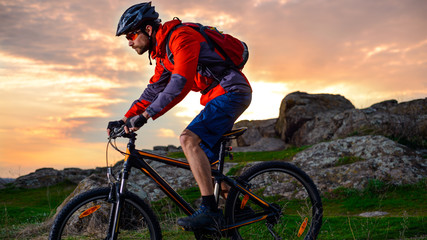 Cyclist Riding Mountain Bike on the Spring Rocky Trail at Beautiful Sunset. Extreme Sports and...