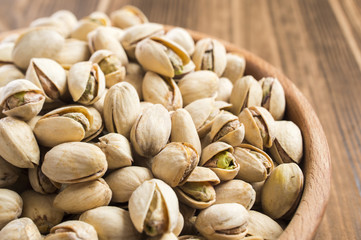 parted ripe pistachio nuts in a bowl on a wooden table