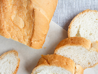 Fresh bread baguette and slices for breakfast on a gray tablecloth closeup flat view