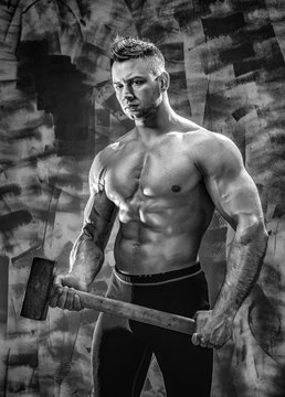 athlete and hammer. guy with a nice toppless muscle fitness body, bodybuilder coach hold big metal hammer
