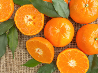 Tangerines and leaves on rustic textiles close-up of a flat view