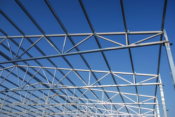 Galvanized steel roof truss construction frames with deep blue sky in the background