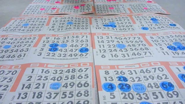 People daub ink on bingo cards in bingo hall time lapse.