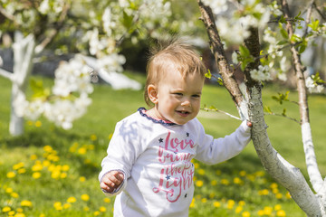 Happy little baby girl on the meadow with yellow flowers