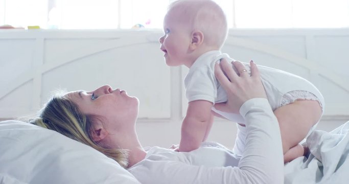 The best moments from life, a loving happy young mother hugs a nursing son, on a snow-white blanket, on a white background. concept of love, family, and happiness