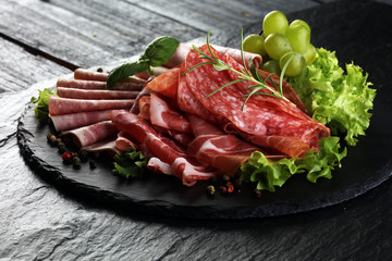 Food tray with delicious salami, pieces of sliced ham, sausage, tomatoes, salad and vegetable - Meat platter with selection