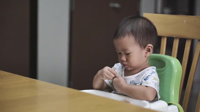 1 year and 3 months Asian baby eating chicken with bone by himself