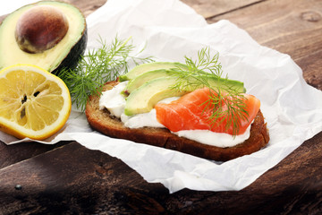 Bread with avocado and smoked salmon for lunch table. Sharing antipasti on party or summer picnic...