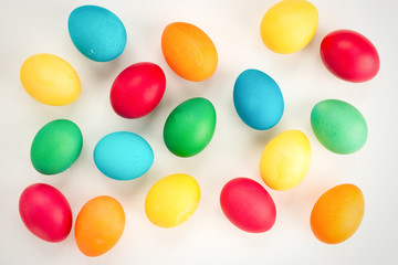 Multicolored easter eggs, on a white wooden background. The concept of a holiday and a happy Easter. With space for text