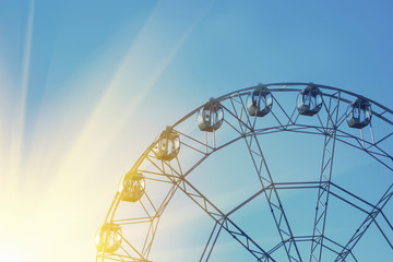 Ferris wheel against a blue sky with the sun