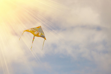 Colorful kite flying high in the blue sky with sunlight