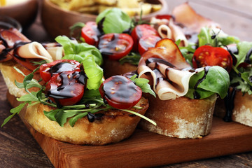 Italian antipasti wine snacks set. Cheese variety, Mediterranean olives, pickles, Prosciutto di Parma, tomatoes, artichokes and wine in glasses