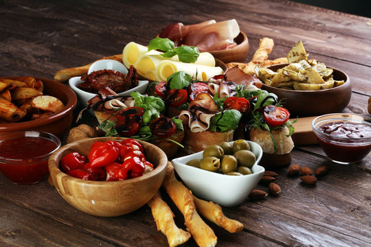 Italian antipasti wine snacks set. Cheese variety, Mediterranean olives, pickles, Prosciutto di Parma, tomatoes, artichokes and wine in glasses