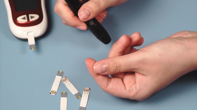 Close up self-testing for diabetes. Woman using lancet and glucometer to mesure blood sugar.