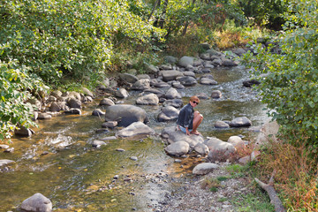 Woman sitting on the rock of mountain river in autumn