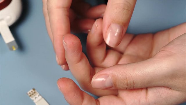Woman using lancet and glucometer to mesure blood sugar. Closeup self-testing for diabetes.