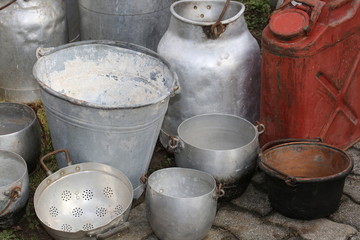 old aluminum containers and an ancient red tank to transport the