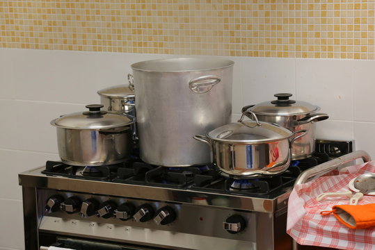 many large steel pots and small saucepan on the stove inside the