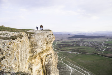 Family with children is on the mountain. White cliff (Ak-Kaya) in the Crimea. Stone blocks and views of the wide steppe. Spring, green grass and clear sky