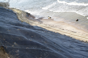 Engineering protection of a landslide slope with reinforcing mesh with anchorage on the seashore. ...