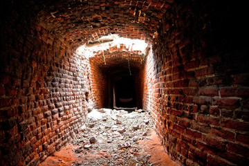 Fototapeta na wymiar An abandoned and collapsed historic underground passage made of red brick