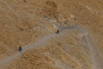 Two hikers crossing the desert at sunny day