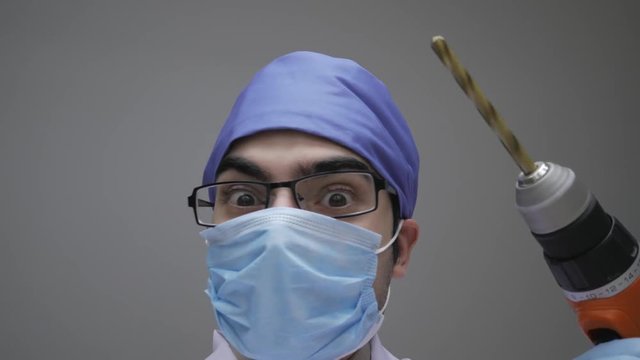 Doctor holding a construction drill while looking scary and dangerous. Personal or patient point of view POV.