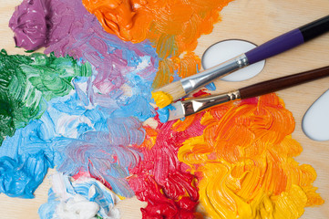 Colored artist's oil paint and brushes on the wooden palette