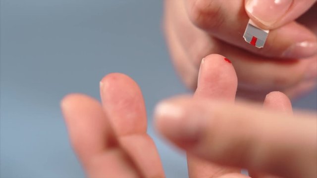 Close up blood sampling from finger. Flesh blood wound from diabetes patient finger and test strip.