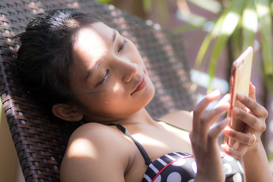 Woman sunbathing on lounger and using mobile phone