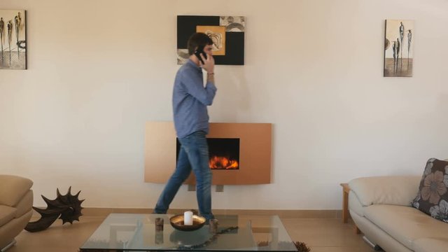 Handsome guy talking on the phone in the stylish room with electric fireplace