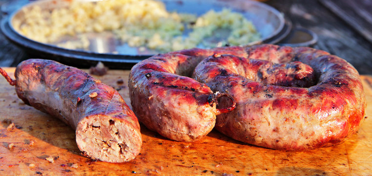 Delicious sausages on wooden plate cooked on barbecue grill