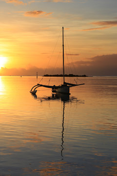 Silhouette of a sail boat at sunset at sea. Amazing colorful sunset on the beach of Moorea, French Polynesia.