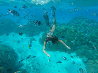 Underwater photo of woman snorkeling and free diving in a clear tropical water at coral reef.