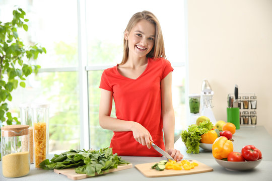 Young beautiful woman cutting vegetables in kitchen