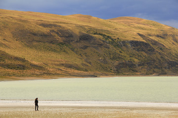 Fototapeta na wymiar Woman walking close to a salt lake in Torres del Paine, Patagonia, Chile