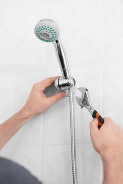 Plumber repairing shower head in bathroom
