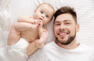 Father lying with cute baby daughter on bed at home