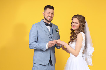 Happy wedding couple on color background
