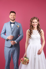 Happy wedding couple on color background