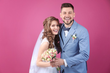 Happy wedding couple dancing on color background