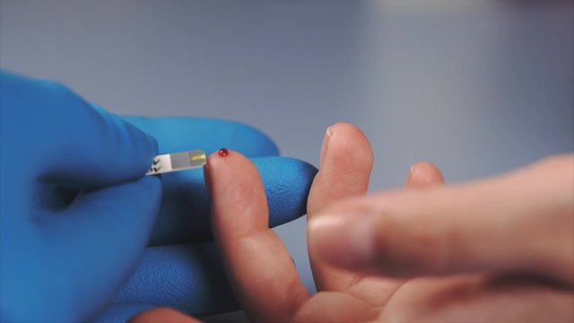 Macro shot of testing for diabetes. Doctor using glucometer to measure female's patient blood sugar.