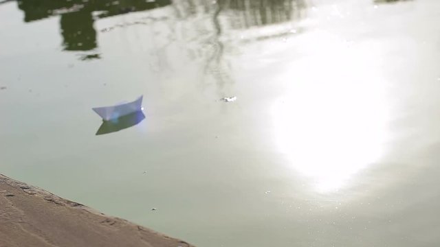 Paper boat floating on the river. Close-up