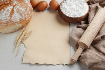 Sheet of paper with space for text and bread on light background