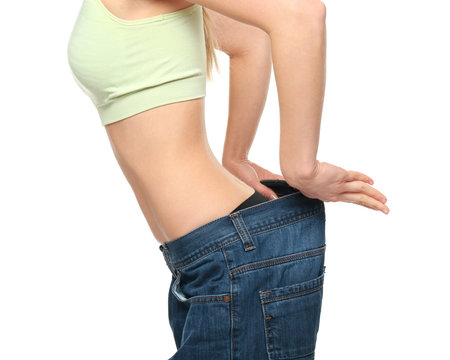 Diet concept. Young beautiful woman in large jeans on white background