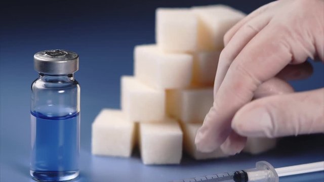Close up concept of diabetes. Vial, sugar cubes and syringe of insulin. Doctor's hand in white gloves.