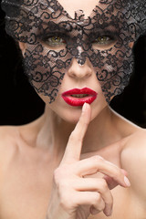 Red lipped female in a carnival mask shushing